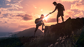A man is assisting a woman up a mountain during sunset.